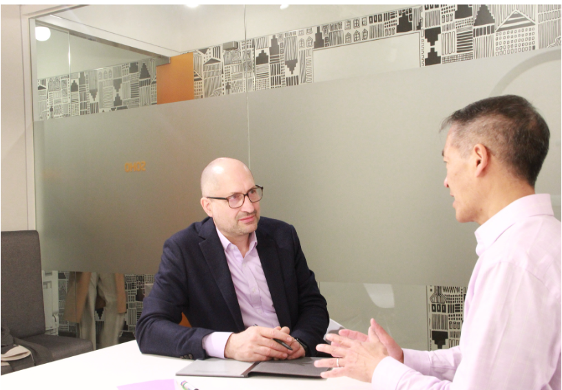 Two colleagues in an attentive one-on-one conversation across a meeting table